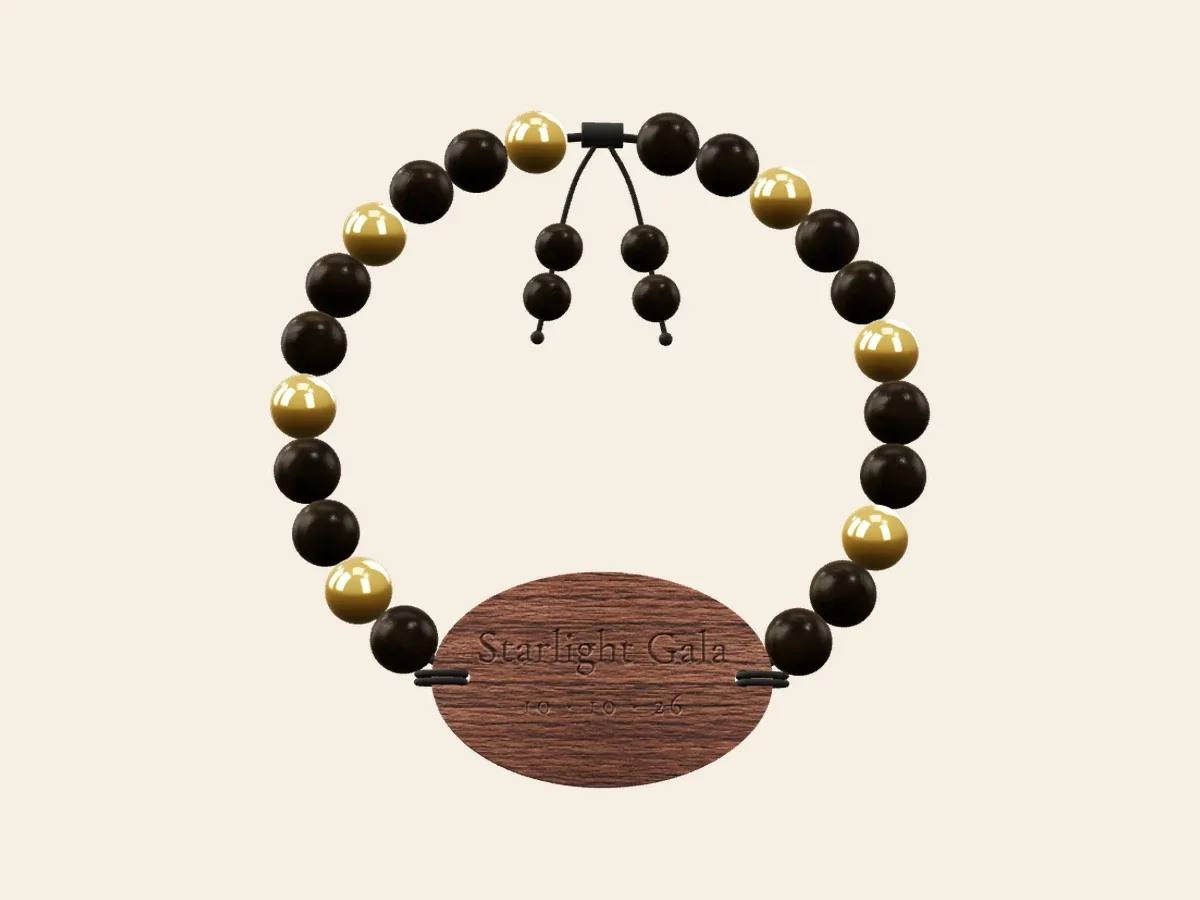 Gala bracelet render with black and gold beads, an adjustable drawstring and an engraved oval wood tag